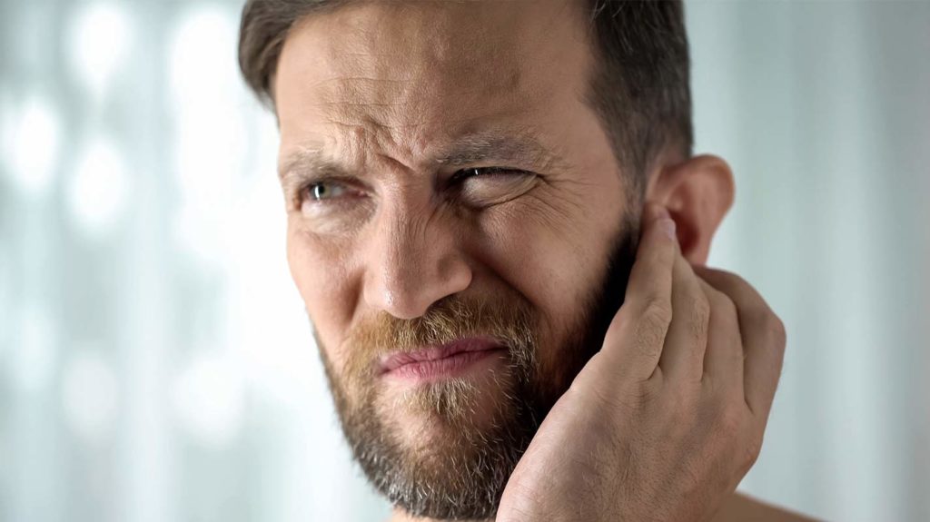 Man scratching ear due to new hearing aids