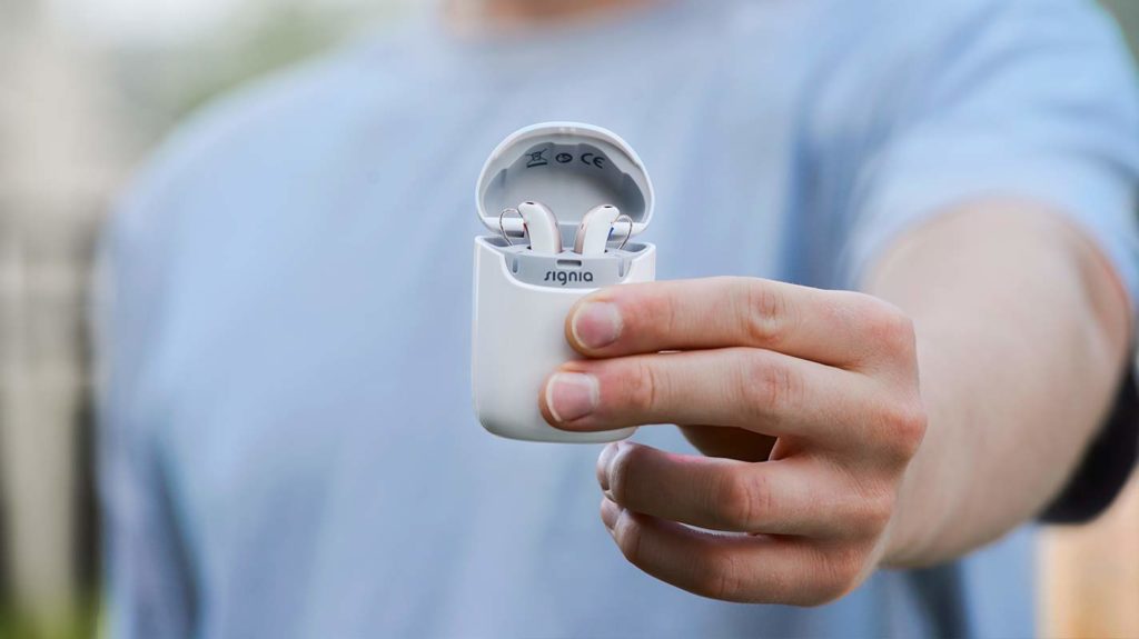 man holding two ears hearing aids
